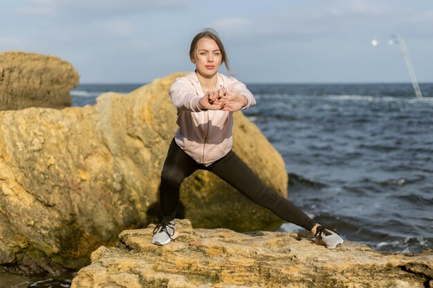 Young fitness woman works out her legs on the wild beach Healthy lifestyle