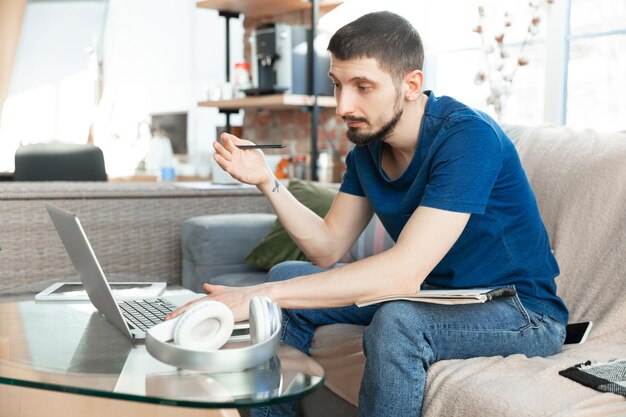 Young focused man studying at home during online courses or free information by hisself