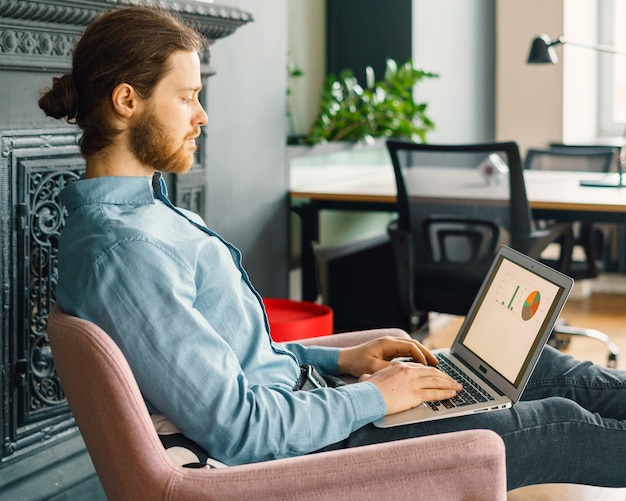 Young focused man trader working on laptop computer