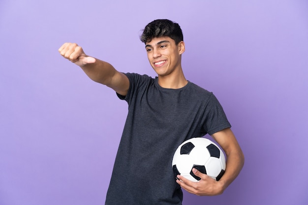 Young football player man over isolated purple wall giving a thumbs up gesture