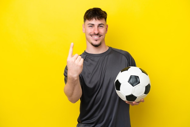 Young football player man isolated on yellow background doing coming gesture