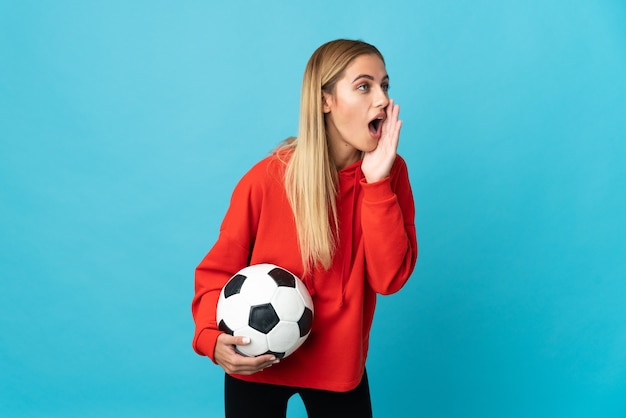 Young football player woman on blue shouting with mouth wide open to the side