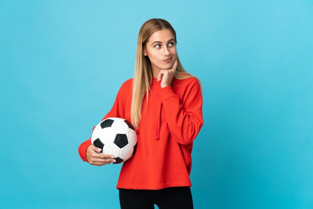 Young football player woman on blue thinking an idea while looking up