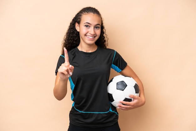 Young football player woman isolated on beige background showing and lifting a finger