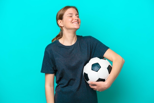 Young football player woman isolated on blue background laughing