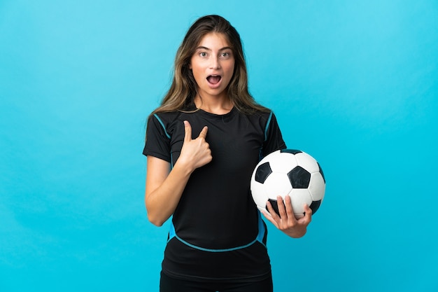 Young football player woman isolated on blue with surprise facial expression