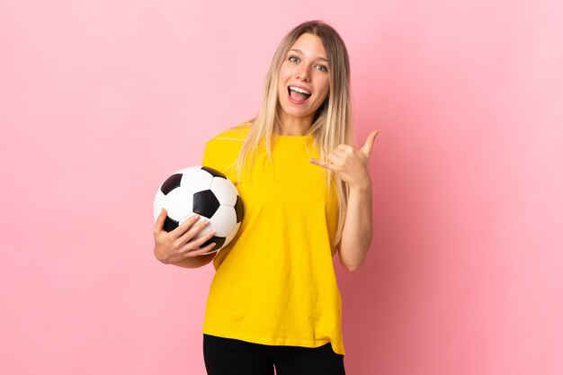 電話ジェスチャーを作るピンクに分離された若いサッカー選手の女性