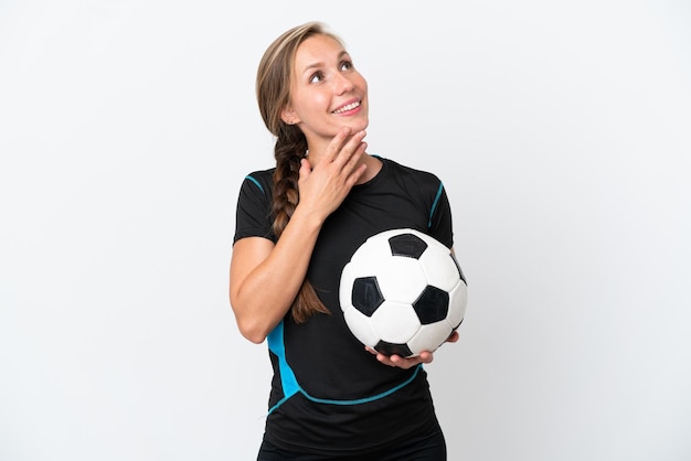 Young football player woman isolated on white background looking up while smiling