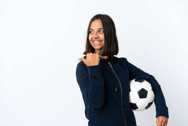 Young football player woman isolated on white background pointing to the side to present a product