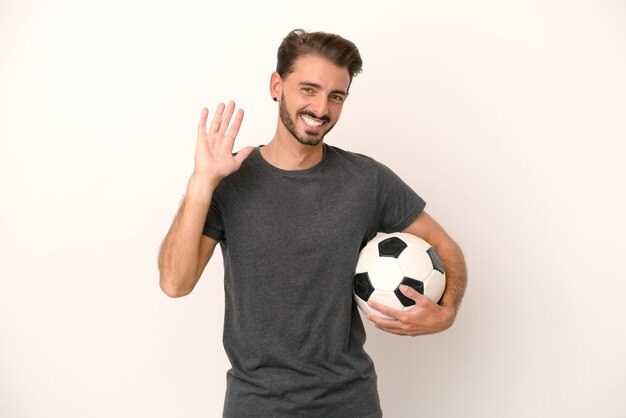 Young football player woman isolated on white background saluting with hand with happy expression