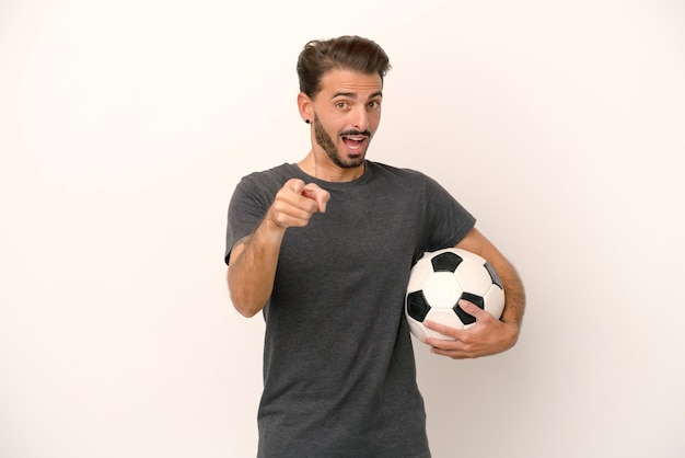 Young football player woman isolated on white background surprised and pointing front