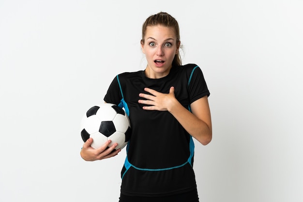 Молодая женщина-футболист, изолированная на белом, удивлена и шокирована, глядя вправо