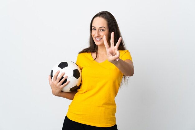 Young football player woman over isolated white wall happy and counting three with fingers