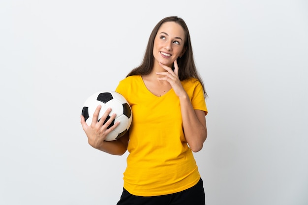 Young football player woman over isolated white wall looking up while smiling