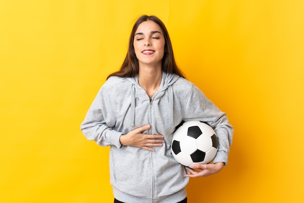 Young football player woman isolated on yellow background smiling a lot