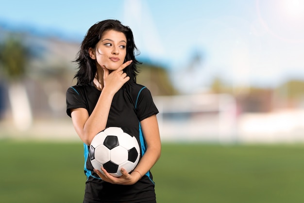 Young football player woman thinking an idea at outdoors