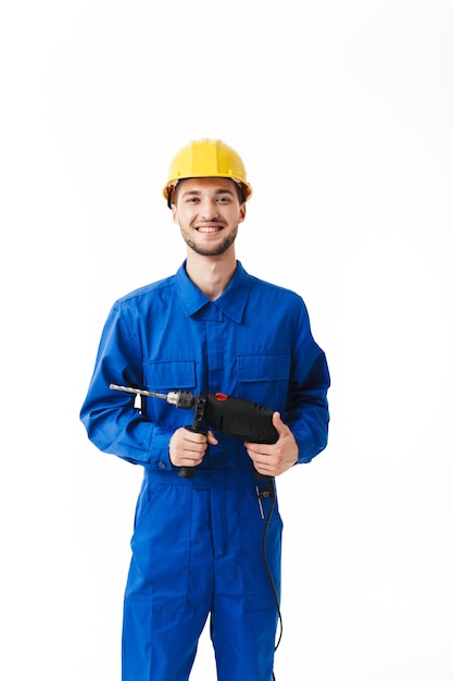 Foto giovane caposquadra in uniforme blu e casco giallo felicemente