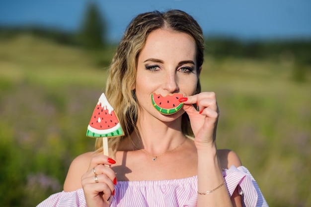 Young freckled woman posing with lollipops in nature.