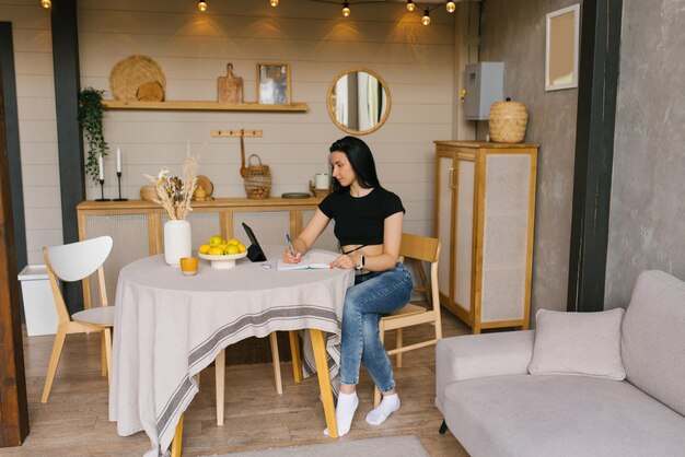 Young freelance woman works at home at a table in the kitchen