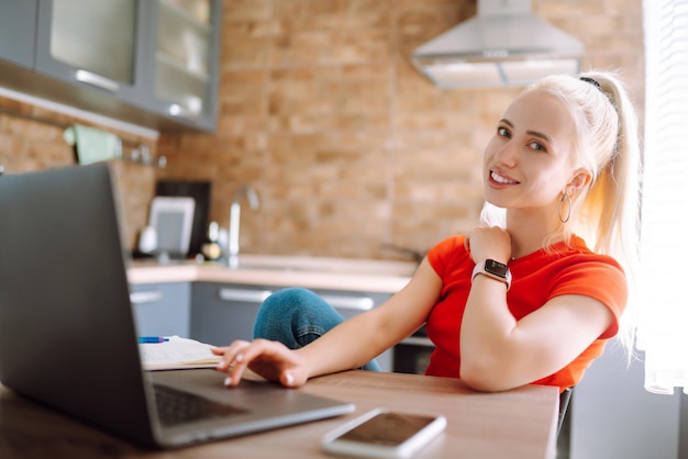 Young freelancer woman works and makes notes while working at home in quarantine lockdown