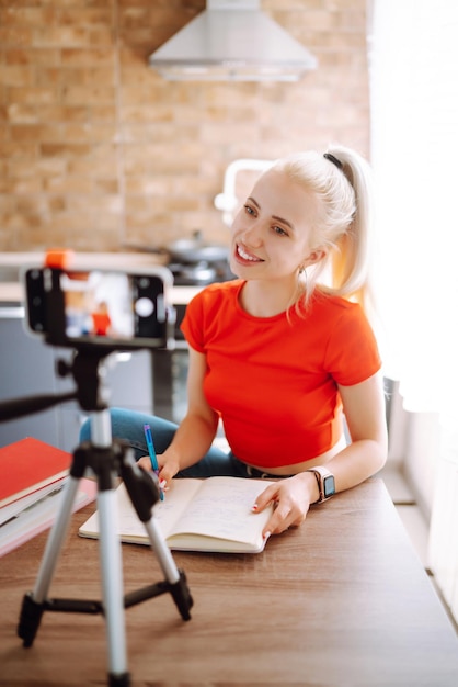 Young freelancer woman works and makes notes while working at home in quarantine lockdown