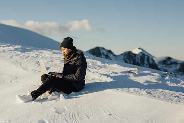 Young freelancer working on a laptop on top of the mountain