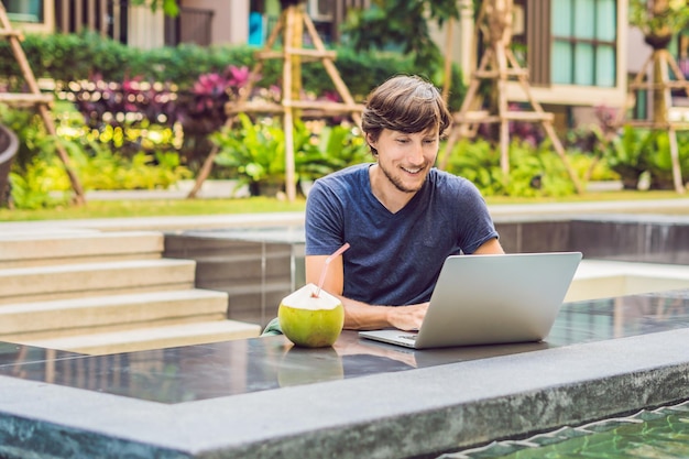 Young freelancer working on vacation next to the swimming pool