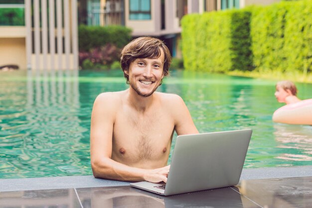 Young freelancer working on vacation next to the swimming pool.