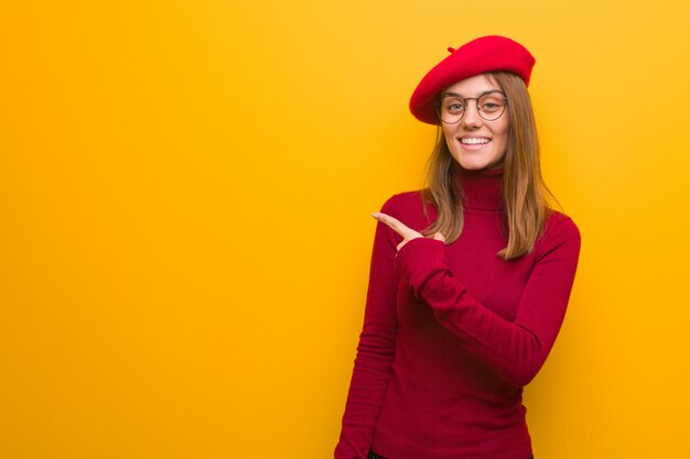 Young french artist woman smiling and pointing to the side