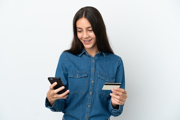 Young French girl isolated on white background buying with the mobile with a credit card