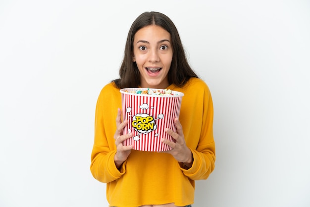 Giovane ragazza francese isolata su sfondo bianco con in mano un grande secchio di popcorn