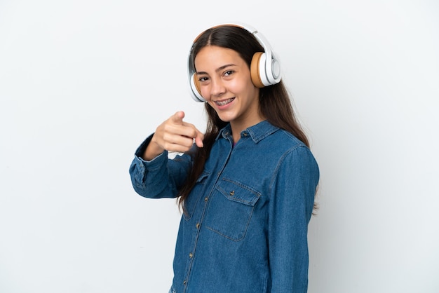 Giovane ragazza francese isolata su sfondo bianco ascoltando musica e indicando la parte anteriore