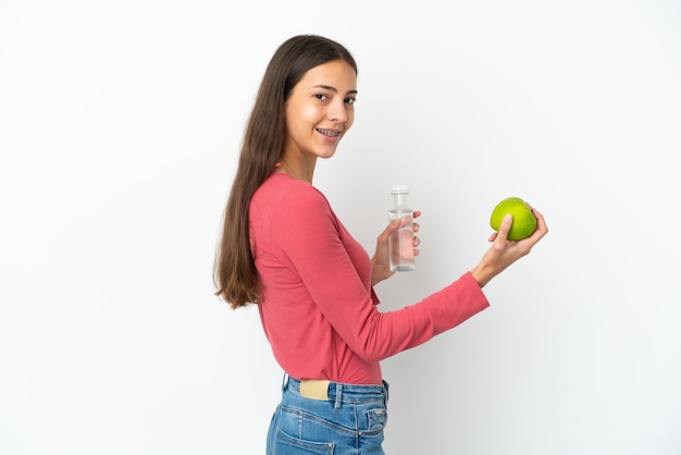 Young French girl isolated on white background with an apple and with a bottle of water