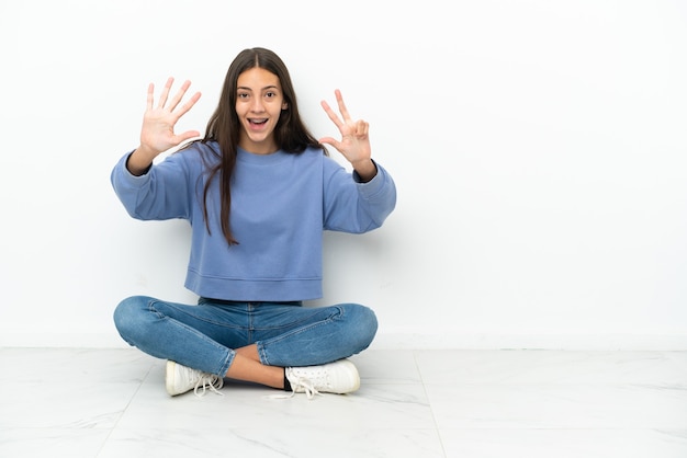 Young French girl sitting on the floor counting eight with fingers