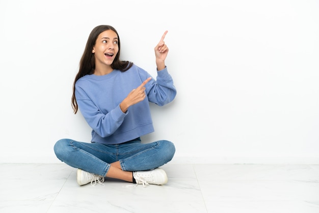 Young French girl sitting on the floor pointing with the index finger a great idea