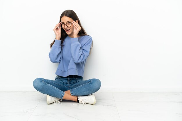 眼鏡をかけて床に座って驚いたフランスの少女