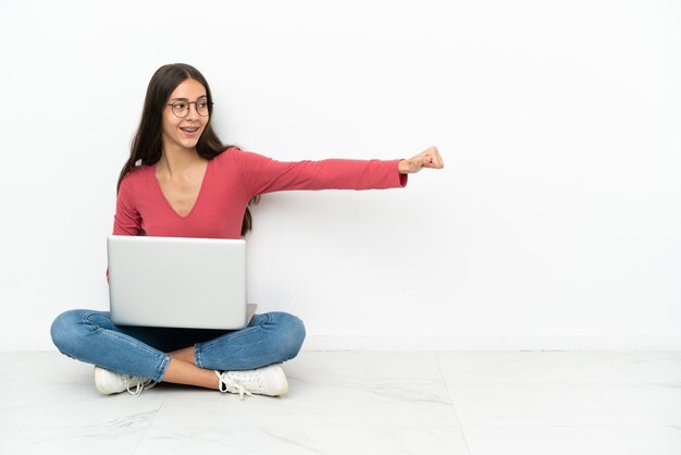 Young French girl sitting on the floor with her laptop giving a thumbs up gesture