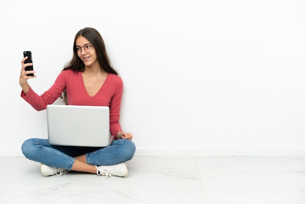 Young French girl sitting on the floor with her laptop making a selfie