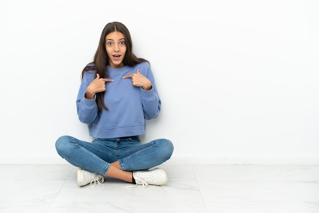 Giovane ragazza francese seduta sul pavimento con un'espressione facciale a sorpresa