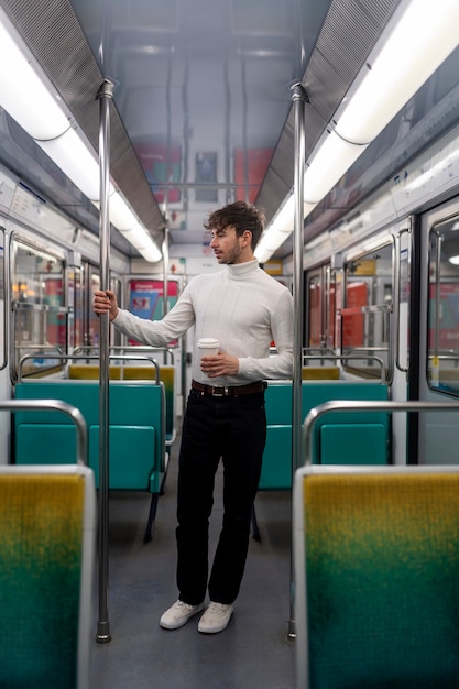 Young french man riding the subway train and drinking coffee