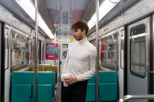 Young french man riding the subway train and drinking coffee