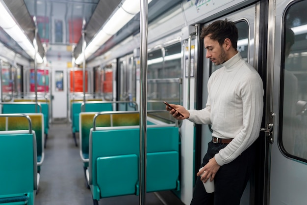 Foto giovane francese che guida il treno della metropolitana e utilizza il suo smartphone