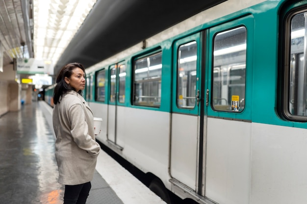 写真 地下鉄の電車を待っているとコーヒーを飲む若いフランス人女性