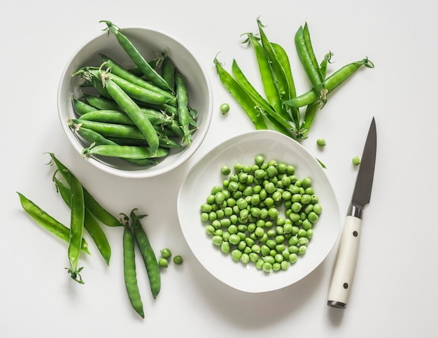 Young fresh green peas on a white background top view