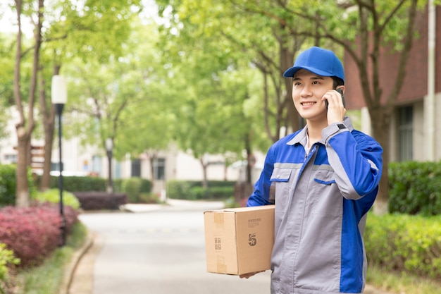 Young friendly delivery man delivering cardboard box at home