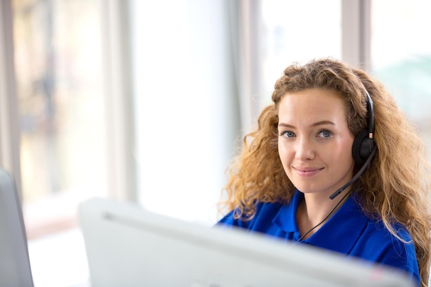 Young friendly operator woman agent with headsets working in a call centre