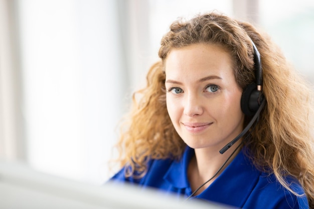 Young friendly operator woman agent with headsets working in a\
call centre