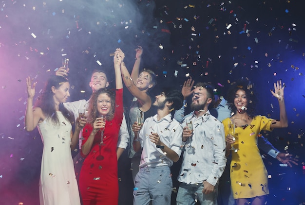 Young friends dancing and having fun at birthday party under flying confetti