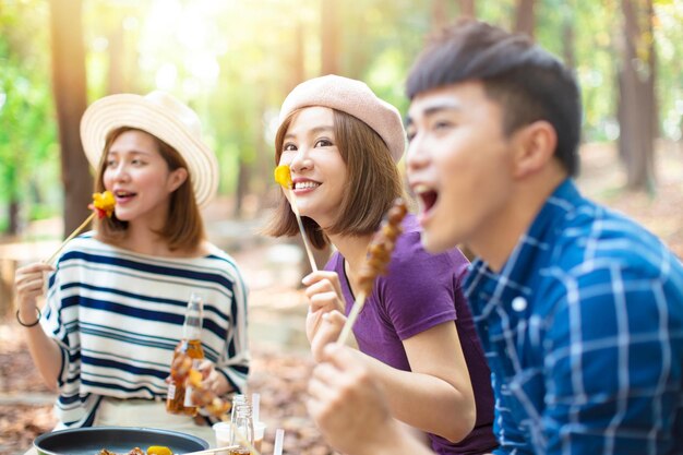 Young friends eating barbecue and having fun cheering