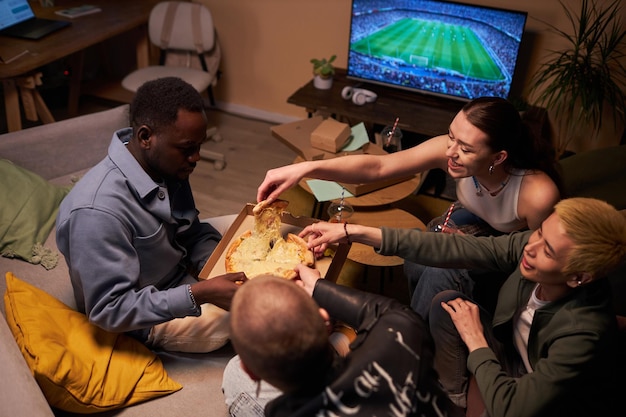 Young friends eating pizza and watching tv